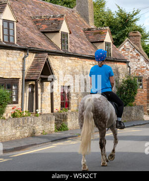 Une femme sur un cheval dans le village pittoresque de South Littleton, Worcestershire, Angleterre, RU Banque D'Images