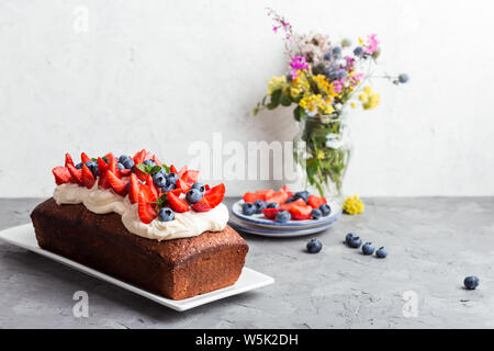 Dessert d'été avec des fraises et des bleuets. Pain gâteau avec glaçage buttercream et surmontée d'été frais mûrs fruits colorés et des baies, sel Banque D'Images