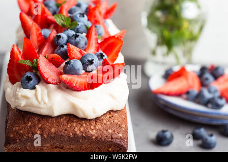 Dessert d'été avec des fraises et des bleuets. Pain gâteau avec glaçage buttercream et surmontée d'été frais mûrs fruits colorés et des baies, sel Banque D'Images