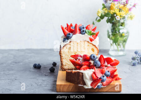 Dessert d'été avec des fraises et des bleuets. Buttercream berry livre avec des tranches de gâteau, fruits et baies colorées sur le dessus, selective focus, clos Banque D'Images