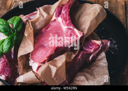 Matières pavé de veau avec des ingrédients, du sel de mer, de l'ail, le basilic herbes prêt à cuire, préparer la nourriture, table en bois en milieu rural, Close up, selective focus Banque D'Images