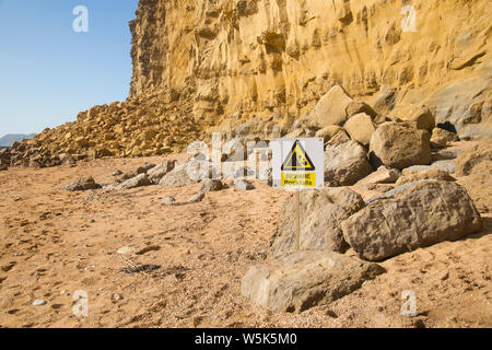 Un panneau d'avertissement indique à du danger de chutes de pierres depuis les falaises à Burton Bradstock, Dorset, Angleterre Banque D'Images