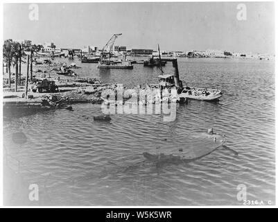 Campagne de bombardement. Europe & Afrique du Nord ; la portée et contenu : Tripoli, Libye, Afrique du Nord. Partie de la bombe-blasted waterfront à Tripoli. L'épave d'un remorqueur se trouve à côté d'un cratère fait par une bombe alliée. Au premier plan on peut voir le hulk submergée d'une barge d'alimentation. Banque D'Images