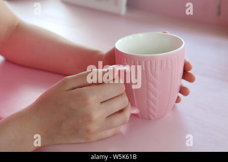 Les mains tenant une tasse à café rose Banque D'Images