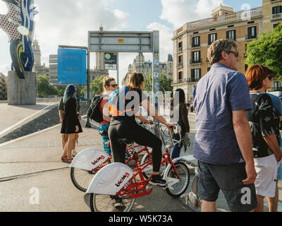 Barcelone, Espagne - 1 juin 2018 : Les piétons les cyclistes hommes et femmes en attente de franchir le pas de la rue animée Sota Muralla au coucher du soleil à El Cap de Barcelone fond statue Banque D'Images