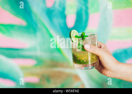 Woman is holding glass of classic mojito cocktail tropical à la mode sur l'arrière-plan. Partie concept. Banque D'Images