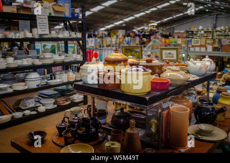 Des piles d'assiettes, de la vaisselle et de la céramique sur les étagères de magasin de charité vue de l'intérieur, la charité pour chic, cycle de recycler, réutiliser et fin. Banque D'Images