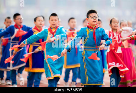 Les élèves des écoles primaires habillés en costumes traditionnels prennent part à une séance de sport à l'école primaire de la ville de Hohhot, en Mongolie intérieure de la Chine du nord Banque D'Images