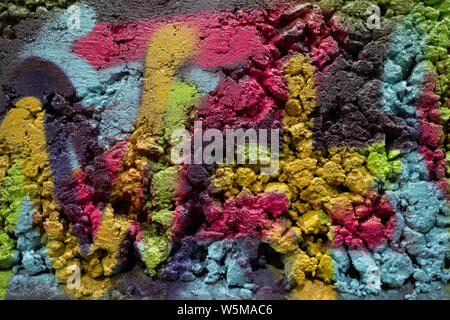 Vue abstraite en gros plan de peinture en aérosol colorée sur une surface de mur en béton texturé rugueux Banque D'Images