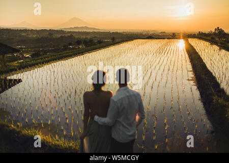 Couple floue dans l'amour de regarder le lever du soleil sur le célèbre monument de Bali rizières en terrasses de Jatiluwih. Beau matin voir l'orange avec la lumière du soleil. Wanderlust Banque D'Images