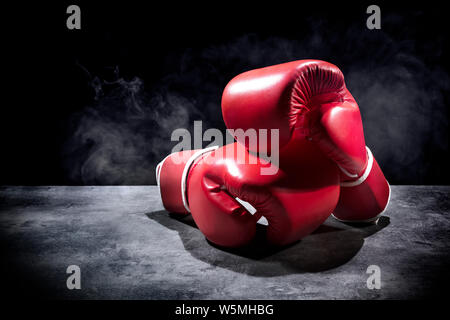 Paire de gants de boxe rouge sur la table de la salle obscure Banque D'Images