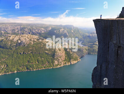 Vue panoramique d'un randonneur debout sur Preikestolen (Pulpit Rock) et à la recherche sur le fjord, la Norvège Banque D'Images