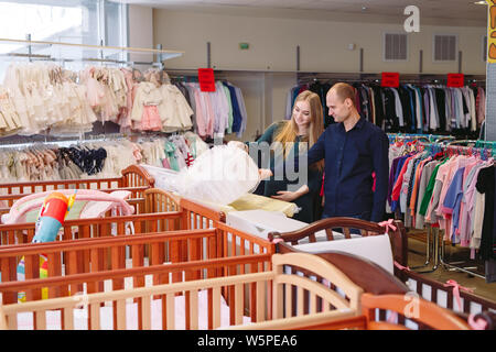 Femme enceinte avec mari choisit un lit bébé dans le magasin Banque D'Images