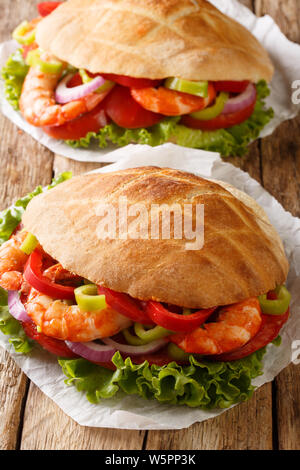 Pita aux crevettes, tomates, poivrons, oignons et salade close-up sur le parchemin sur la table verticale. Banque D'Images