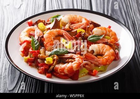 Partie de crevettes frites avec des champignons et des légumes d'été gros plan sur une assiette sur la table horizontale. Banque D'Images
