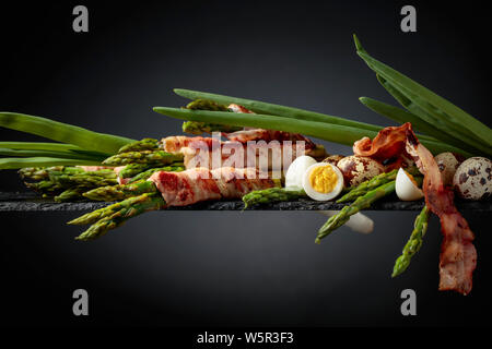 Asperges au bacon. L'asperge verte enrobé de bacon avec des oeufs de cailles et l'oignon vert. Copier l'espace. Banque D'Images