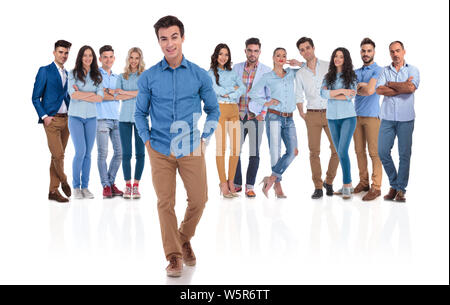 Ambiance détendue et informelle chef d'équipe devant son groupe avec les mains dans les poches sur fond blanc. Ils portent des chemises bleues et un jean Banque D'Images