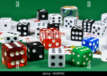 Close up image conceptuelle avec un tas de dés de couleur sur plusieurs cartes à jouer , sur la surface verte Banque D'Images