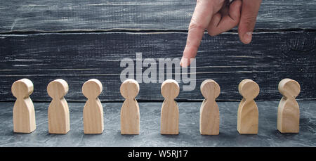 Un businessman's hand pointe sur une figure humaine en bois. Le concept de la recherche de travailleurs, gestion des ressources humaines. L'embauche et volnenie employer Banque D'Images