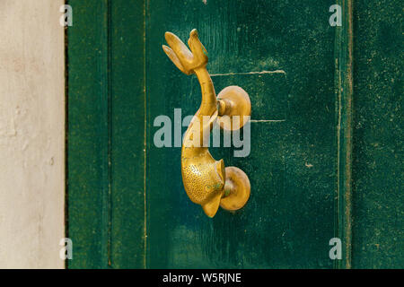 La texture d'une vieille porte en bois en bois avec poignées en métal sous la forme d'un dauphin sur l'île de Malte Banque D'Images