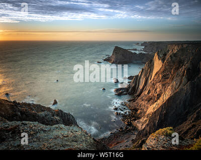 Les derniers rayons de lumière illuminant le seacliffs à Arrifana sur la côte atlantique du Portugal Banque D'Images