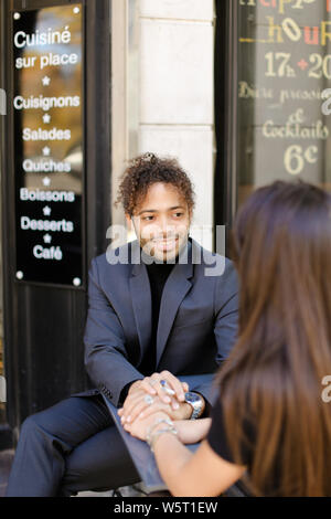 Se concentrer sur l'afro american boy holding female hands et assis au café de la rue. Concept de l'amour et dating homme noir. Banque D'Images