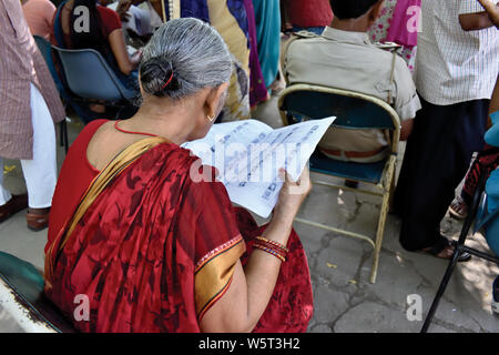 Patna, Bihar, Inde - le 19 mai 2019 : une femme âgée tente de trouver son nom dans la liste des électeurs pendant le jour du scrutin de l'élection générale en 2019. Banque D'Images