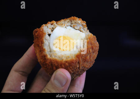 Une cuisine britannique traditionnelle. Scotch egg à moitié mangé. L'oeuf cuit dur enveloppé dans la chair à saucisses enrobées de chapelure et au four ou frits. Pique-nique commun Banque D'Images