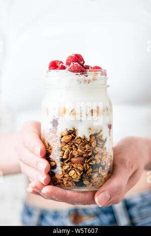 Yaourts à la framboise et d'avoine muesli dans un pot dans les mains de la jeune fille. Nettoyer alimentaires, les régimes, la perte de poids concept Banque D'Images