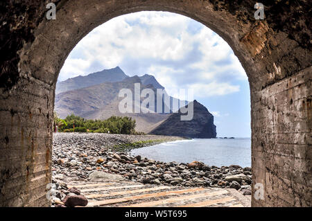 Plage de rochers avec la falaise de roque de las Marciegas vu du tunnel à pied vers le port. Partie orientale de Gran Canaria. Placé dans L Banque D'Images