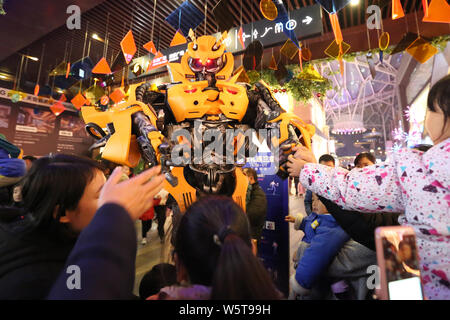 Un étudiant portant un deux mètres de haut réplique grandeur de Bumblebee est entouré par les clients à un centre commercial dans la ville de Xi'an, dans le nord-ouest de la Chine Banque D'Images