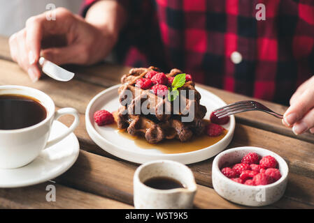 Bon chocolat belge gaufres avec du sirop et des framboises pour le petit-déjeuner ou un dessert dans le café. Selective focus Banque D'Images