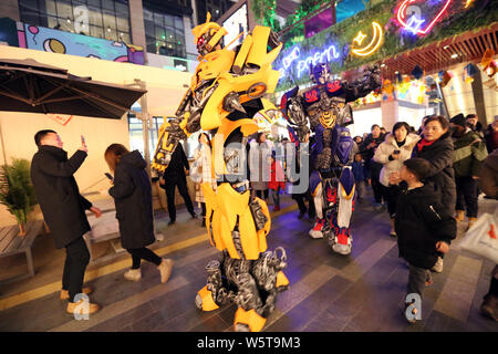 Un étudiant portant un deux mètres de haut réplique grandeur de Bumblebee est entouré par les clients à un centre commercial dans la ville de Xi'an, dans le nord-ouest de la Chine Banque D'Images