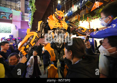 Un étudiant portant un deux mètres de haut réplique grandeur de Bumblebee est entouré par les clients à un centre commercial dans la ville de Xi'an, dans le nord-ouest de la Chine Banque D'Images