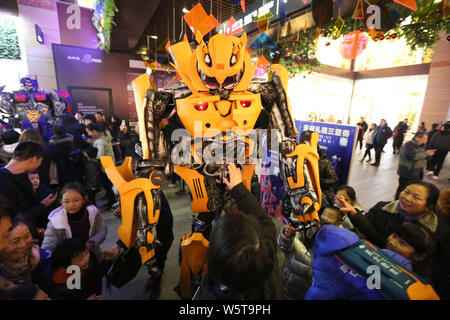 Un étudiant portant un deux mètres de haut réplique grandeur de Bumblebee est entouré par les clients à un centre commercial dans la ville de Xi'an, dans le nord-ouest de la Chine Banque D'Images