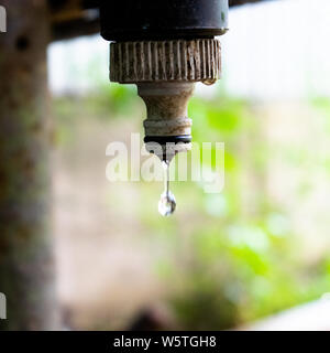 Une goutte d'eau tombe d'une sale et d'un robinet d'eau rouillée - thème ingénierie de l'eau Banque D'Images