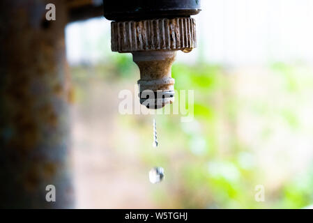 Une goutte d'eau tombe d'une sale et d'un robinet d'eau rouillée - thème ingénierie de l'eau Banque D'Images