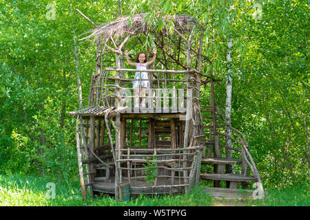 Petite fille heureuse dans une maison de l'arbre en bois sur une journée ensoleillée. Kid se réjouit dans l'été. Le concept de l'été. Banque D'Images