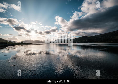 La fin de l'après-midi les rayons du soleil filtrant à travers les nuages sur le Loch Linnhe en Ecosse avec des montagnes qui se découpent dans la distance Banque D'Images