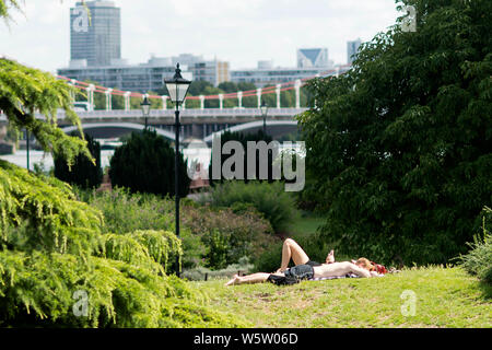 29/07/2019. Battersea, Londres, Royaume-Uni. Les gens le soleil sur l'herbe dans Battersea Park sur une journée ensoleillée et chaude Banque D'Images