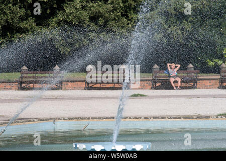 29/07/2019. Battersea, Londres, Royaume-Uni. Une femme de soleil sur un banc à côté de l'eau des fontaines dans Battersea Park sur une chaude journée ensoleillée. Banque D'Images