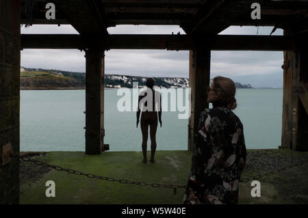 Femme visiteur à Antony Gormley's statue dans le port de Folkestone kent Banque D'Images