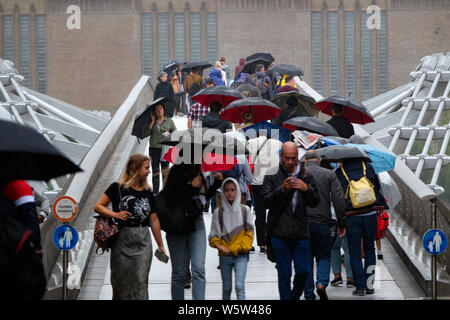 Millennium Bridge, London, UK. 30 juillet 2019. Parasols et de fortes averses comme personnes traversent le pont du Millénaire. Crédit : Matthieu Chattle/Alamy Live News Banque D'Images