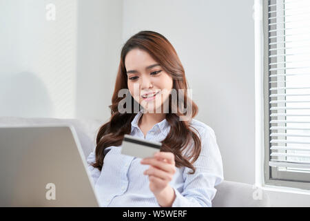 Une belle utilisation ordinateur portable et sa carte bancaire tout en faisant du shopping à partir de la maison sans vivre canapé Banque D'Images