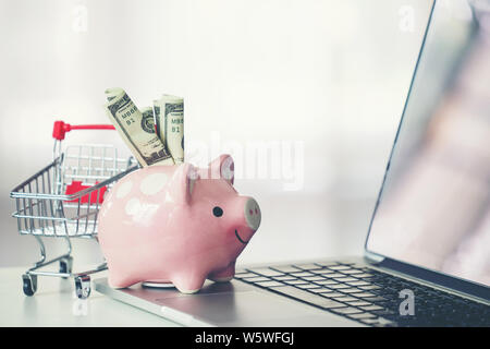 Panier et tirelire avec ordinateur portable sur le bureau, concept d'achat en ligne Banque D'Images