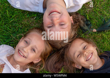 Trois sœurs portrait d'été. Jolies filles sont allongés sur l'herbe et souriant. smiling children outdoor. Concept de l'été Banque D'Images