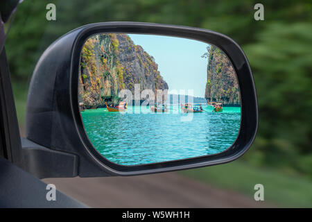 Le paysage dans le miroir d'une voiture weda , sur la campagne environnante. Dans le miroir du côté de la voiture se reflète la mer des rochers et des bateaux. Le concept de Banque D'Images