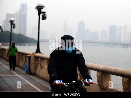 --FILE--un cycliste portant un masque contre la pollution de l'air promenades dans le smog lourd dans la ville de Guangzhou, province du Guangdong en Chine du sud, le 11 décembre 2013. Banque D'Images