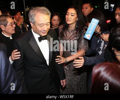 **Hors TAIWAN**L'actrice chinoise Gong Li, droite, prend en charge réalisateur Taiwanais Ang Lee avec ses mains comme ils vont à la soirée banquet après le chinois Banque D'Images