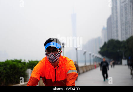 --FILE--un cycliste portant un masque contre la pollution de l'air promenades dans le smog lourd dans la ville de Guangzhou, province du Guangdong en Chine du sud, le 11 décembre 2013. Banque D'Images